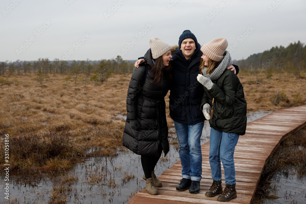 a guy and two girls walk in nature. Friends laugh and smile