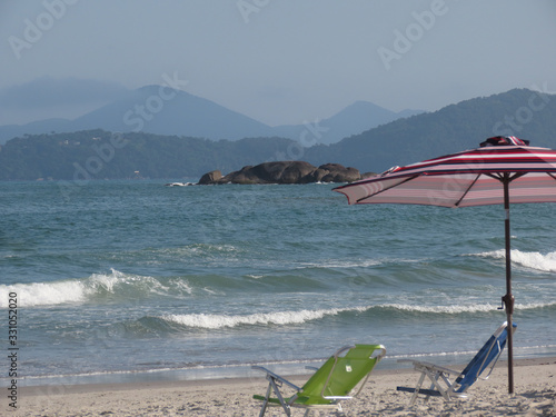 Empty beach and umbrella with no people on the sand and empty chairs