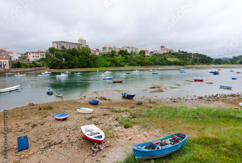 San Vicente de la Barquera, small medieval town in Cantabria, (Spain). Scenic mountain and sea landscape in the north of Spain, with green meadows and boats in a beautiful setting.