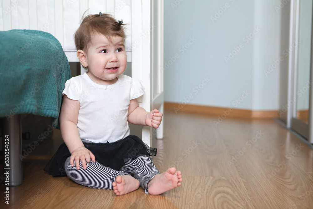 Baby girl sitting on the floor in room, smiling and happy Caucasian child