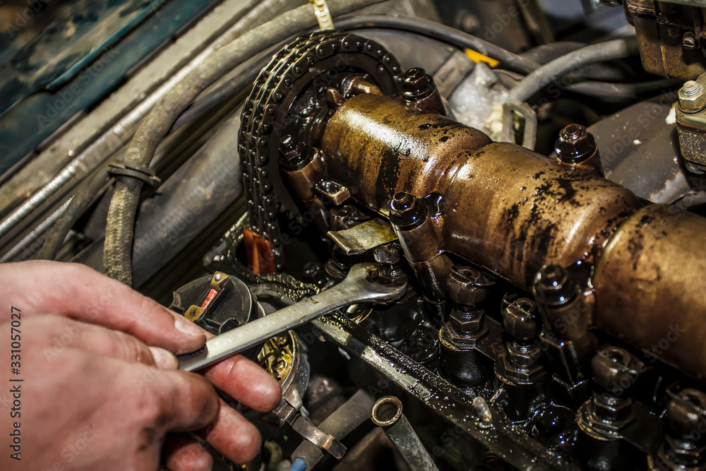 Car engine without valve cover. The mechanic is setting up the valve. Setting the valve of the engine by hand. Close-up. Car engine without valve cover. The mechanic is setting up the valve. Setting the valve of the engine by hand. Close-up.