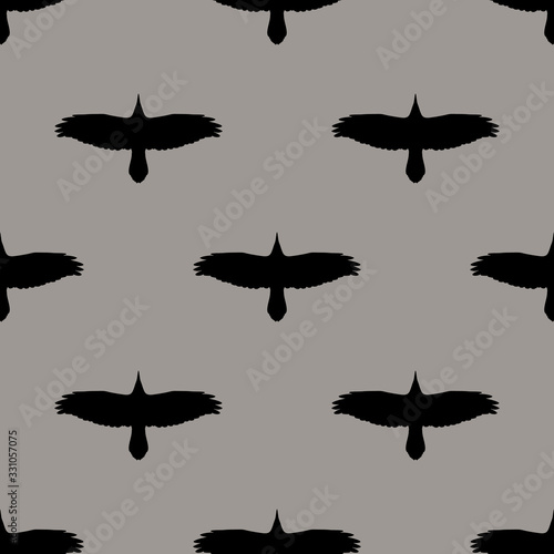 Seamless monochrome animal pattern with silhouettes of soaring raven or crow birds.