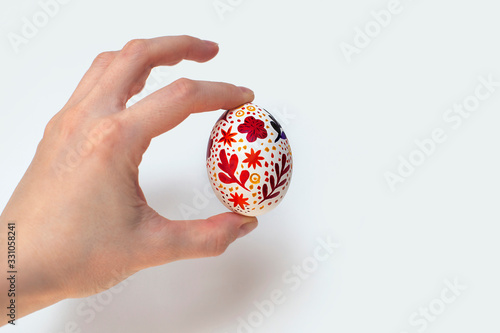 Easter egg with watercolor floral print. In hand. Handmade painting. On isolated background. 