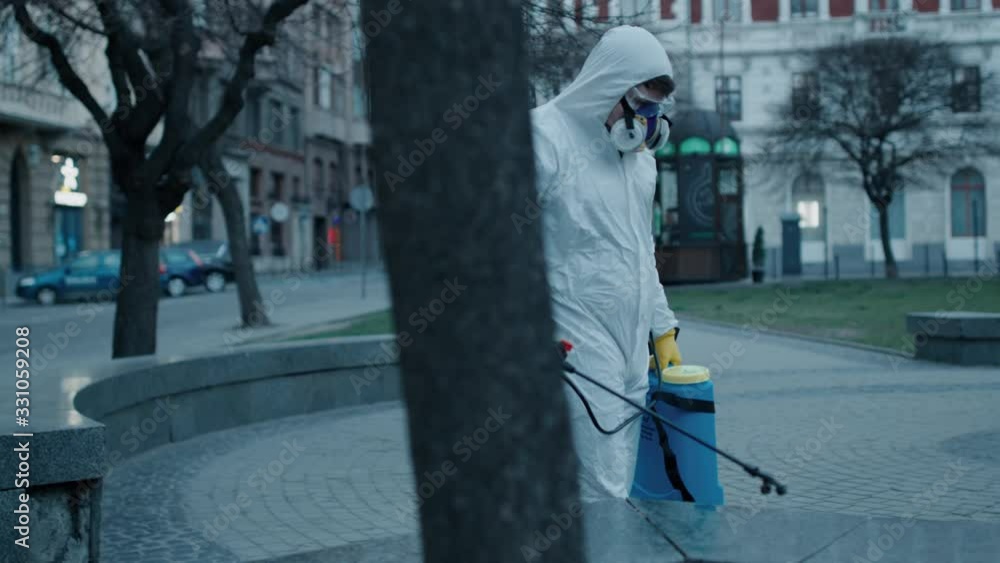 Man in chemical protect wear spray eampty city street with anti bacterial liquid Man in chemical protect wear spray eampty city street with anti bacterial liquid
