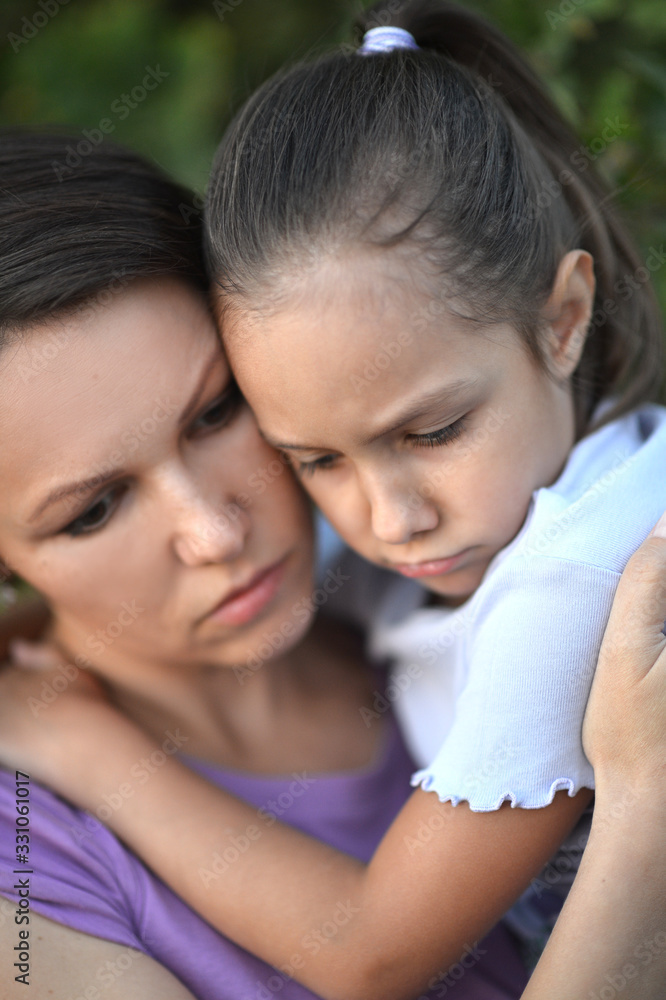 Close up portrait of sad woman and girl hugging