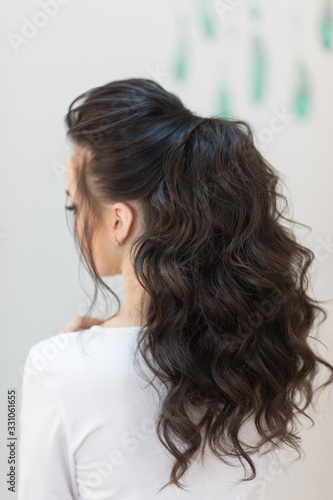 Young brunette girl with a fashionable hairstyle look from the back