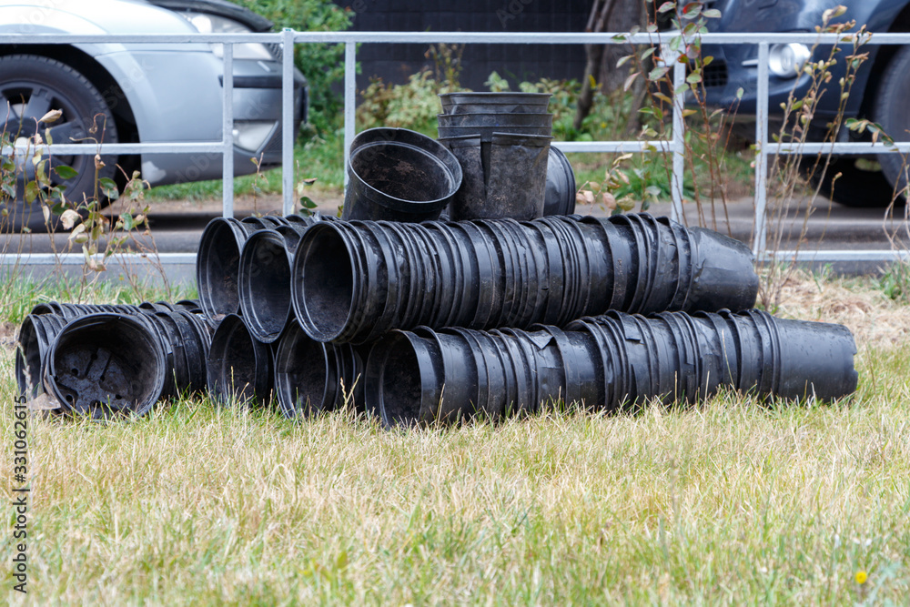 Black plastic pots on the grass near the fence. Black plastic pots on the grass near the fence.