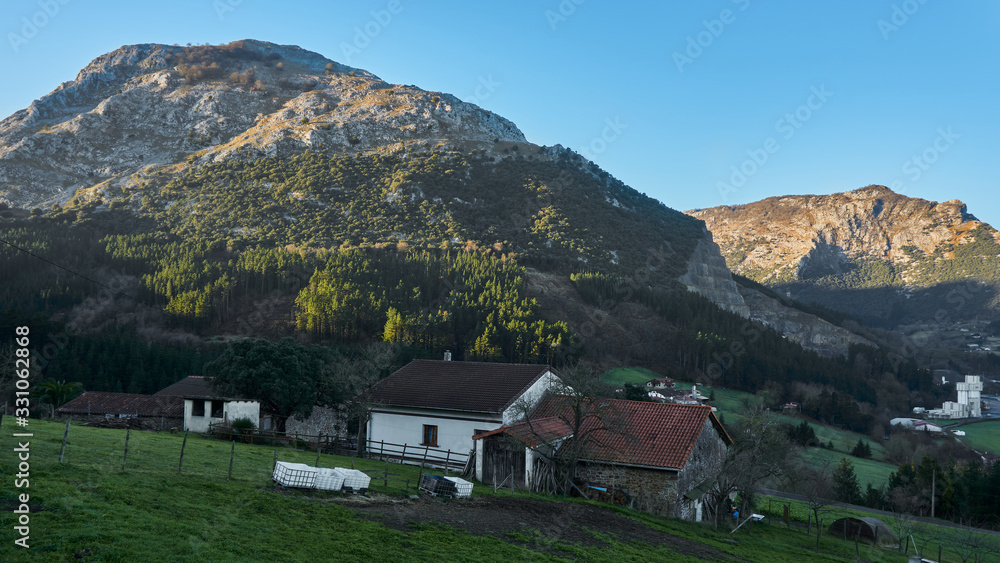 Farm next to mountains at dawn Typical Basque farm next to fields Urkiola Natural Park