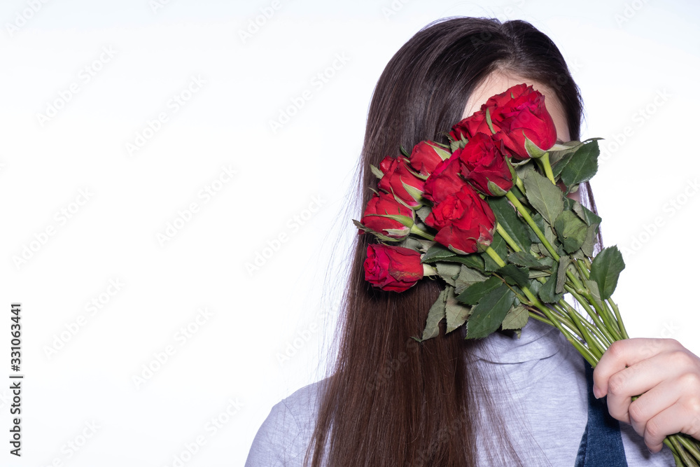 Naklejka premium girl hiding behind a bouquet of bright red roses