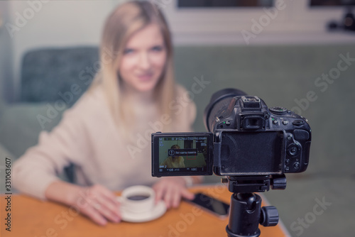 Beautiful girl blogger in front of camera/ Beautiful blogger woman explains while online live streaming in front of camera. Night working influencer. Focus camera