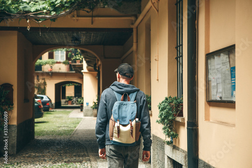 A tourist or traveler with a backpack is looking for accommodation that he has booked or a student returned home after studying or on vacation.