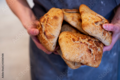 Close up of person holding freshly baked bread rolls in an artisan bakery. photo