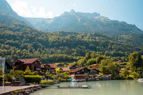 Fototapeta Naklejka Na Ścianę i Meble -  View of Brienz lake with clear turquoise water. Sailing boats. Traditional wooden houses on the shore of Brienz lake in the village of Iseltwald, Switzerland