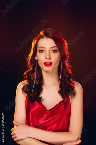 Elegant woman in red dress looking at camera isolated on black