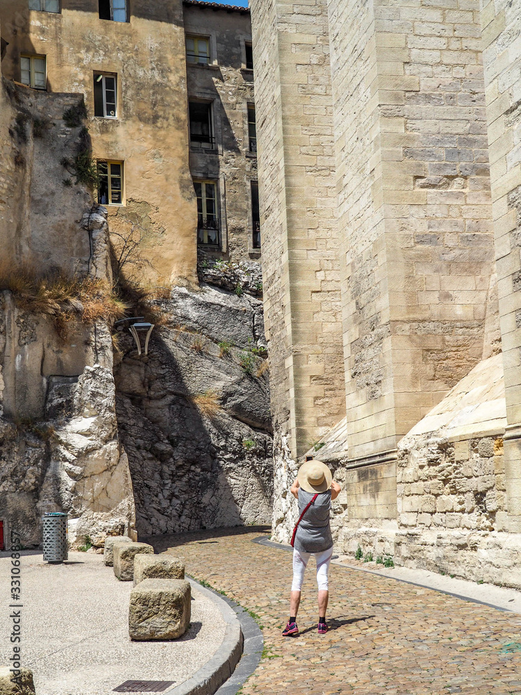 Tourist stops to photograph a curved stone road leading between ancient stone buildings in Provence.
