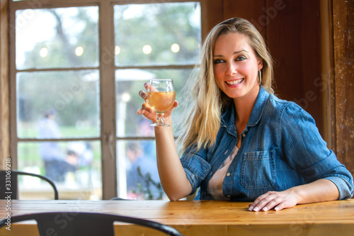 Beautiful blonde woman enjoying a craft beer in a tulip glass at a local brewery pub on a sunny weekend day photo