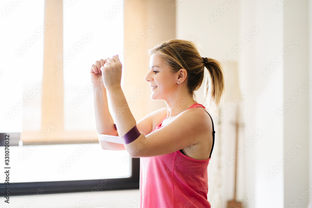 beautiful blonde caucasian athlete woman doing exercises with elastic band in living room at home beautiful blonde caucasian athlete woman doing exercises with elastic band in living room at home
