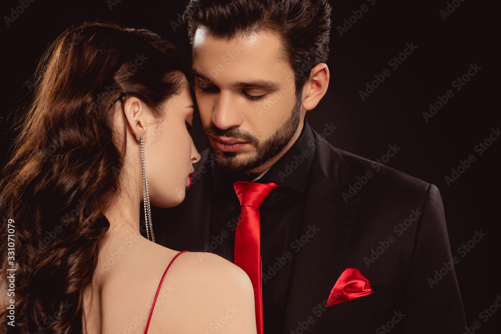 Beautiful woman standing near handsome man in formal wear isolated on black