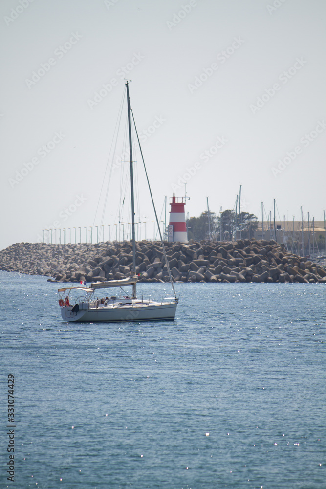 Fototapeta premium Boat in front of lighthouse in Portugal