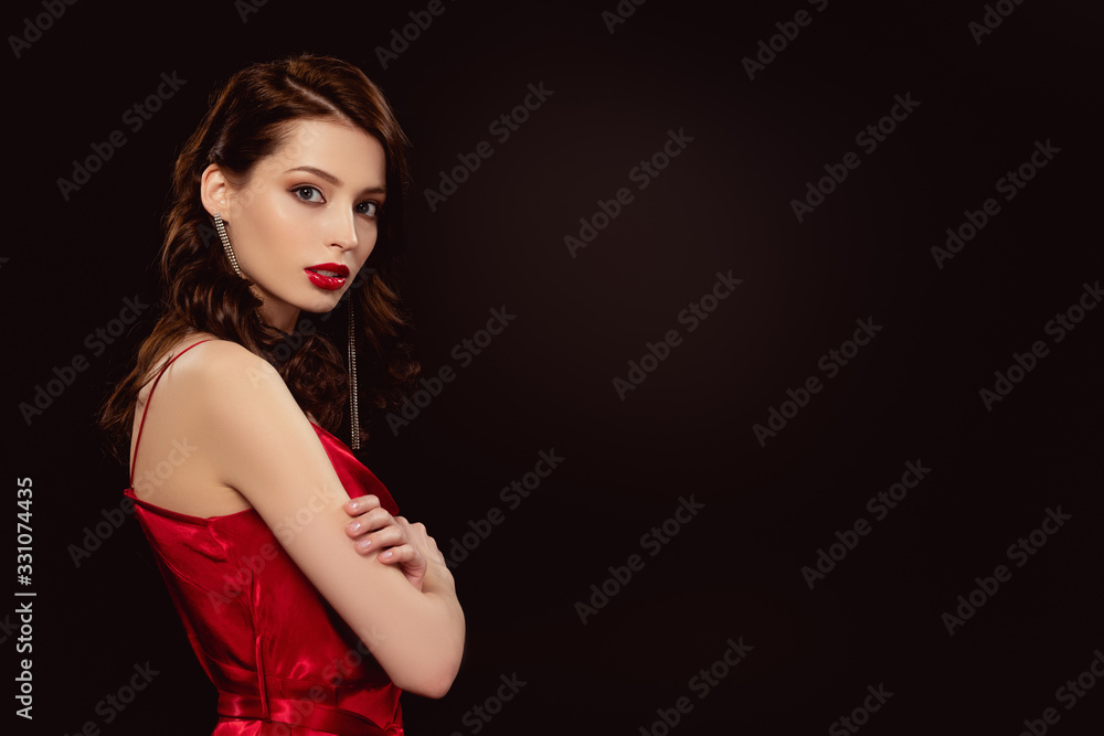 Side view of elegant girl with crosses arms looking at camera isolated on black Side view of elegant girl with crosses arms looking at camera isolated on black