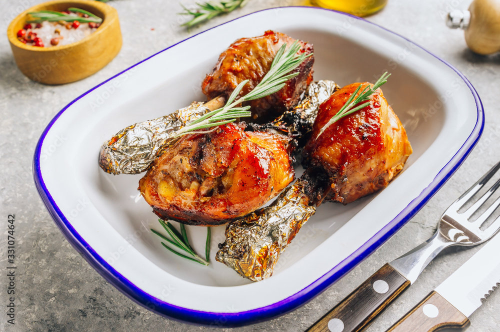 Grilled chicken drumstick bbq with rosemary on a stone gray background.
