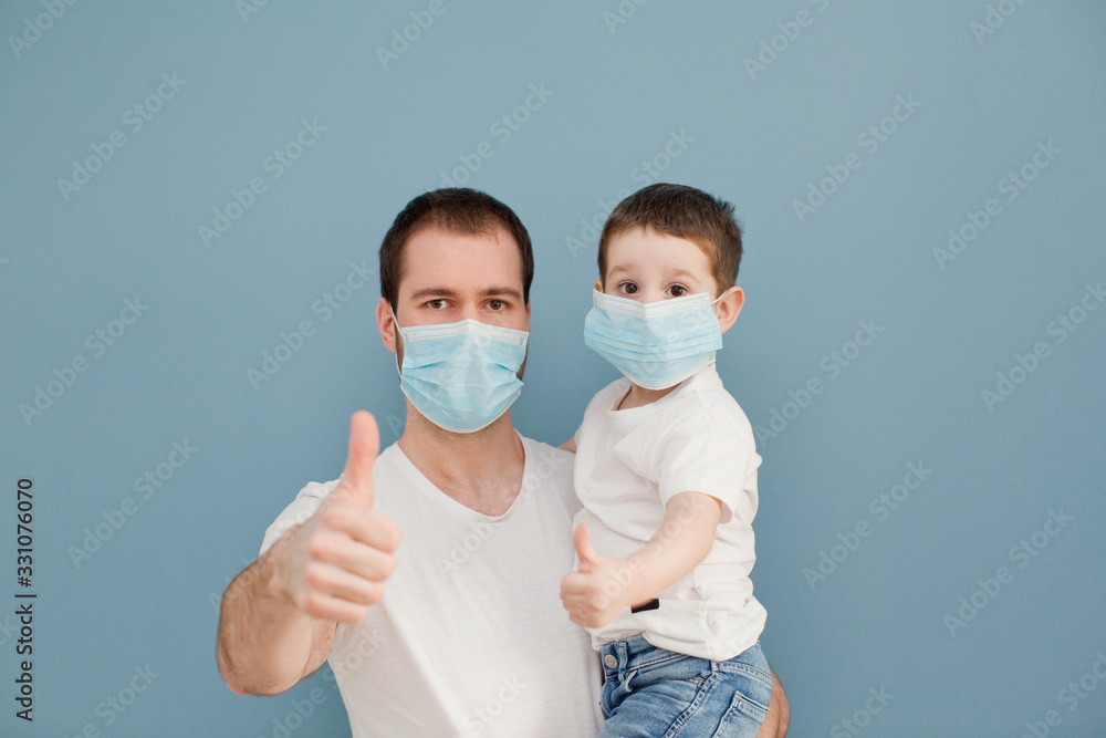 young father and his toddler son wearing surgical masks giving thumbs up to protection during the quarantine