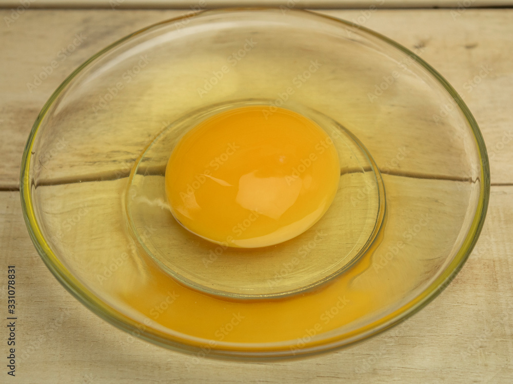 Broken chicken egg in a glass plate on a wooden background Broken chicken egg in a glass plate on a wooden background