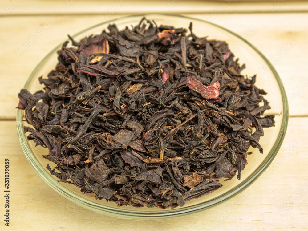 Dry hibiscus tea leaves in glass plate on wooden background Dry hibiscus tea leaves in glass plate on wooden background