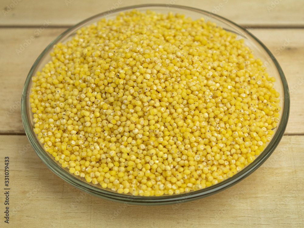 Millet groats on a glass plate on a wooden background Millet groats on a glass plate on a wooden background