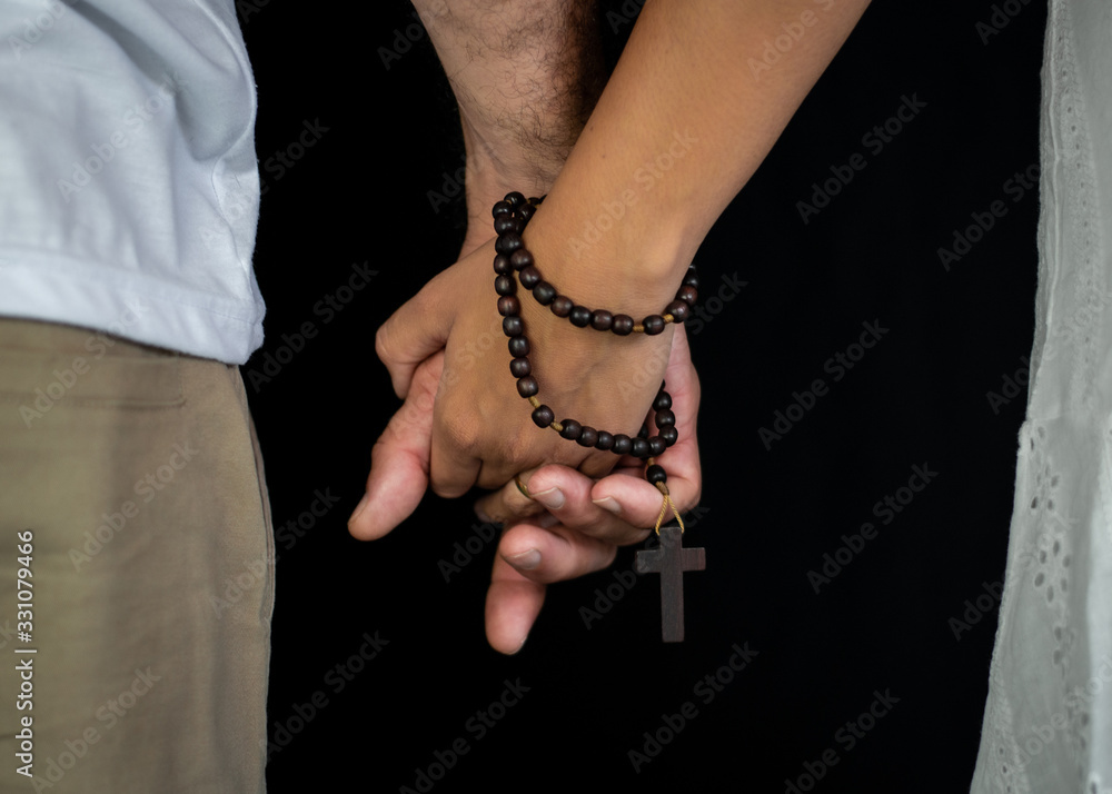 Casal de mãos dadas com terço religioso