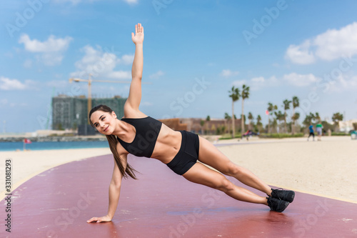 Fitness woman strength training her body core muscles with yoga pose. Athlete planking on one arm doing side plank and hip lift.