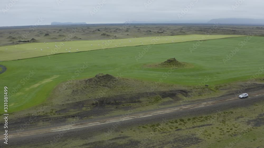 Typical Southern Icelandic setting. Small craters, green countryside. Suv along the dirt road. Typical Southern Icelandic setting. Small craters, green countryside. Suv along the dirt road.