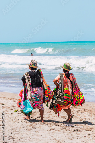 two wayuu women walking along the beach