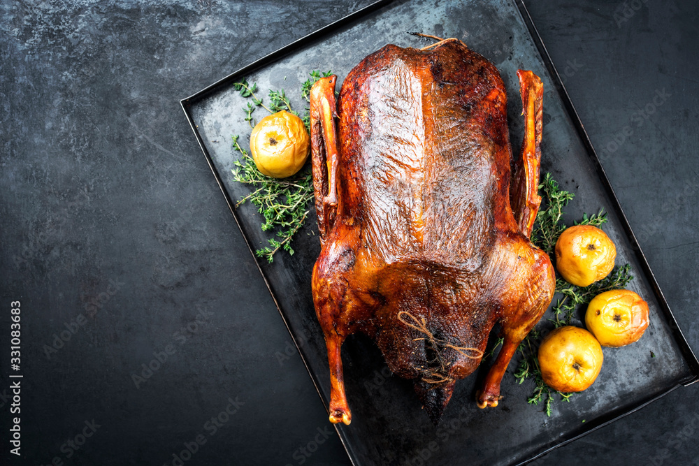 Traditional roasted stuffed Christmas goose with apples and herbs as top view on a rustic metal tray with copy space left - obrazy, fototapety, plakaty 