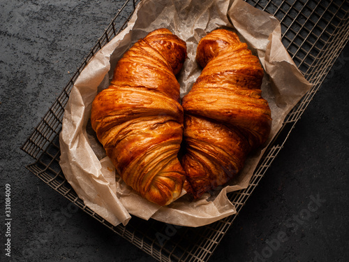 Stampa su tela two big delicious croissants on parchment on a dark concrete background
