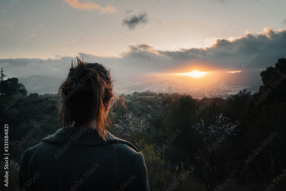 Over shoulder view of woman looking at sunset over city