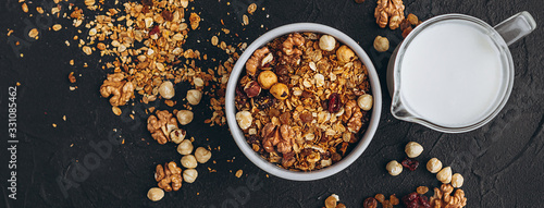 a delicious and crunchy oatmeal granola with honey, nuts, dried fruits and grains is poured out of the praml package into a plate.  food photography background photo