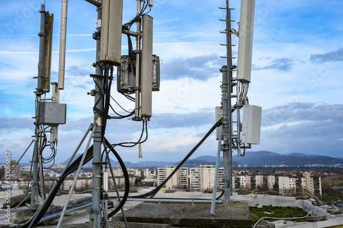 Cellular radio telecommunication network antenna mounted on a metal pole providing strong signal waves from the top of the roof across big city 