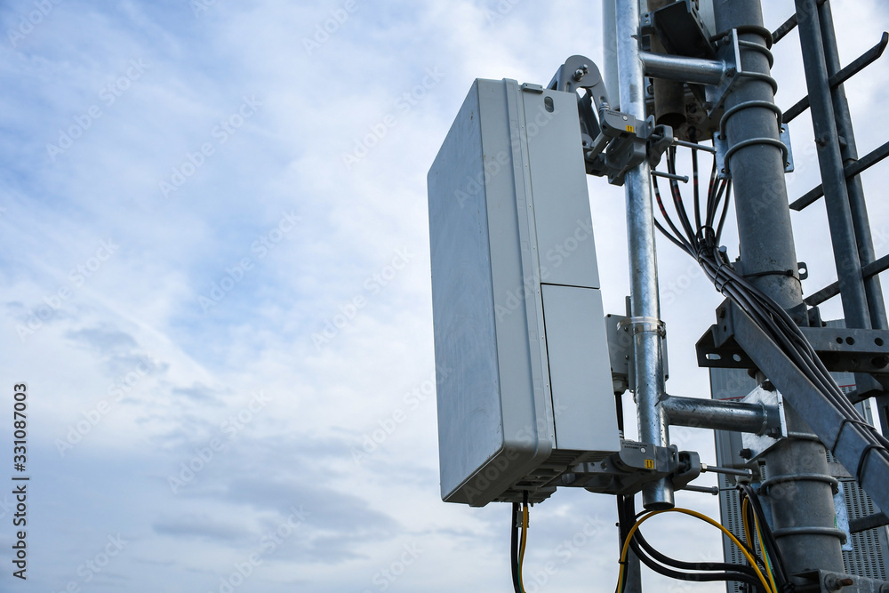 5G new radio telecommunication network antenna mounted on a metal pole providing strong signal waves from the top of the roof across big city 5G new radio telecommunication network antenna mounted on a metal pole providing strong signal waves from the top of the roof across big city
