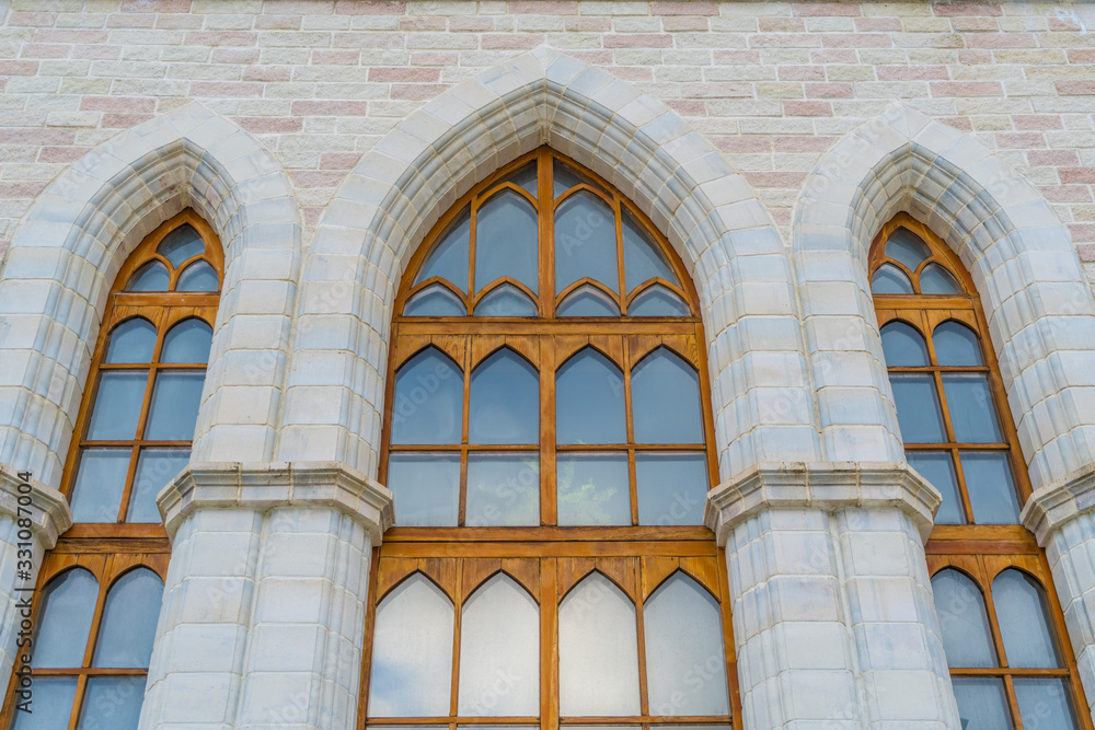 The windows of the arch of the old building in the Gothic style. With a reflection of the blue sky. Facade Interior Texture