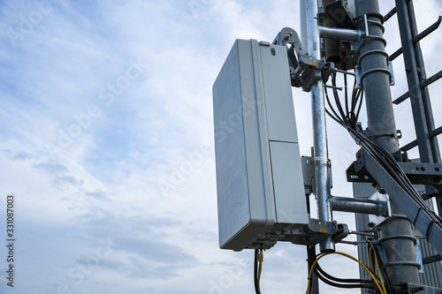 5G new radio telecommunication network antenna mounted on a metal pole providing strong signal waves from the top of the roof across big city 