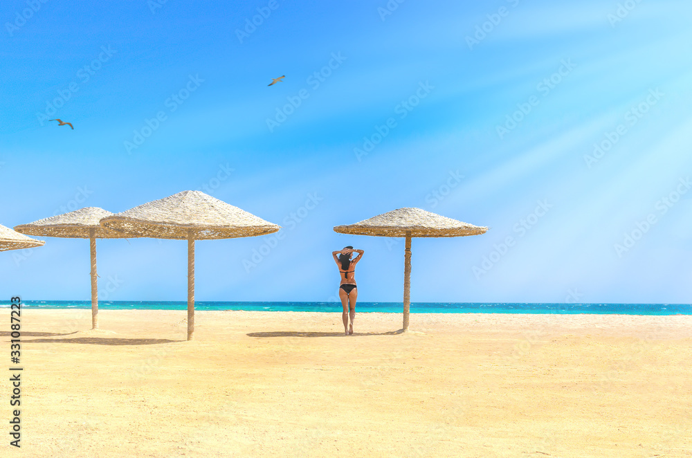 Young woman standing alone on empty sand beach at sea shore Young woman standing alone on empty sand beach at sea shore