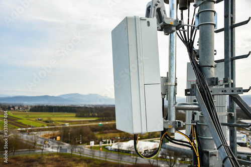 5G new radio telecommunication network antenna mounted on a metal pole providing strong signal waves from the top of the roof across big city 