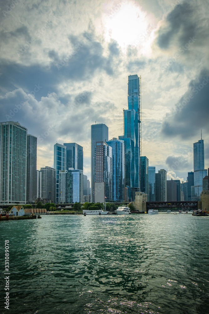 View of Chicago skyline against a backdrop of dramatic clouds. Buildings along the mouth of the Chicago river.
