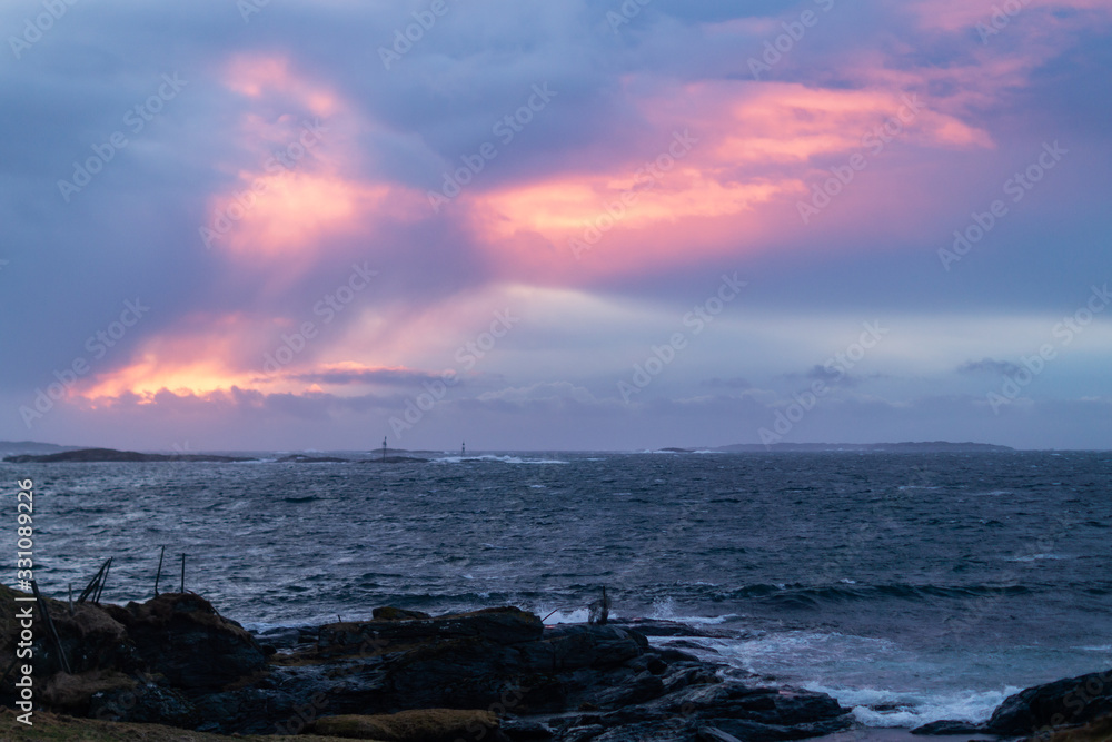 Sunset with waves hitting rocks on the shore line, clouds in the sky Sunset with waves hitting rocks on the shore line, clouds in the sky