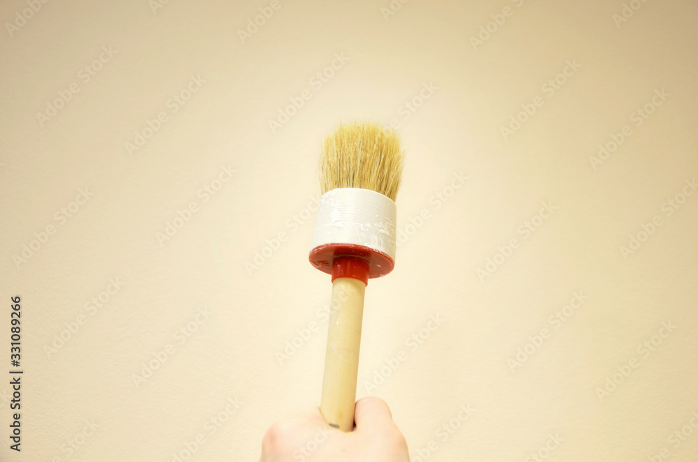 Wooden brush in the hand. The design idea of repair and a new interior of an apartment or house with your own hands. Painting walls and radiators with paint. Wooden brush in the hand. The design idea of repair and a new interior of an apartment or house with your own hands. Painting walls and radiators with paint.