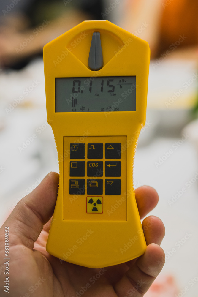 Modern yellow geiger counter in a hand of a person. Measuring