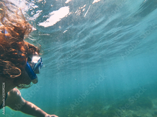 underwater girl snorkeling in crystal clear water beach photo