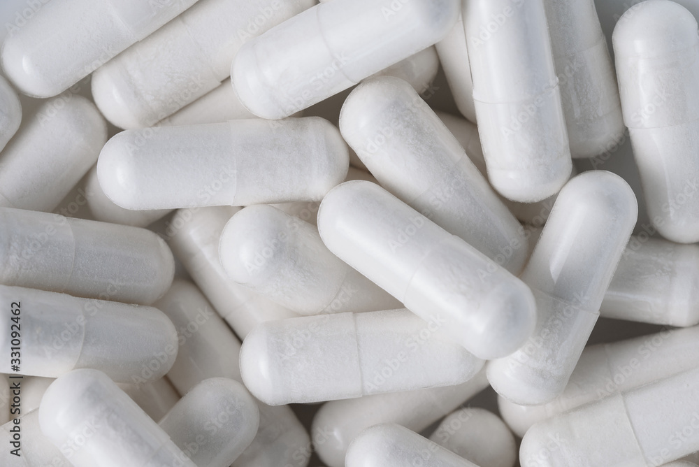 Top view Closeup pile of white antibiotic capsule pills texture. Pharmaceutical production industry. White pills as background texture. Health care. Top view Closeup pile of white antibiotic capsule pills texture. Pharmaceutical production industry. White pills as background texture. Health care.