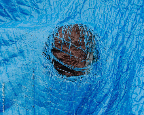 Close up worn blue tarp with tattered hole in center,Fishing Nets
